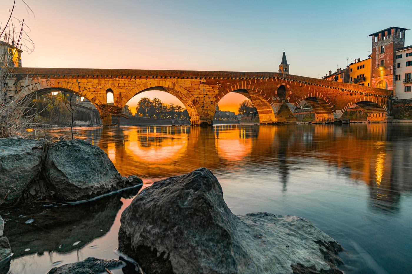 Antico ponte di pietra romano al tramonto, simbolo della rete di competenze e della cooperazione