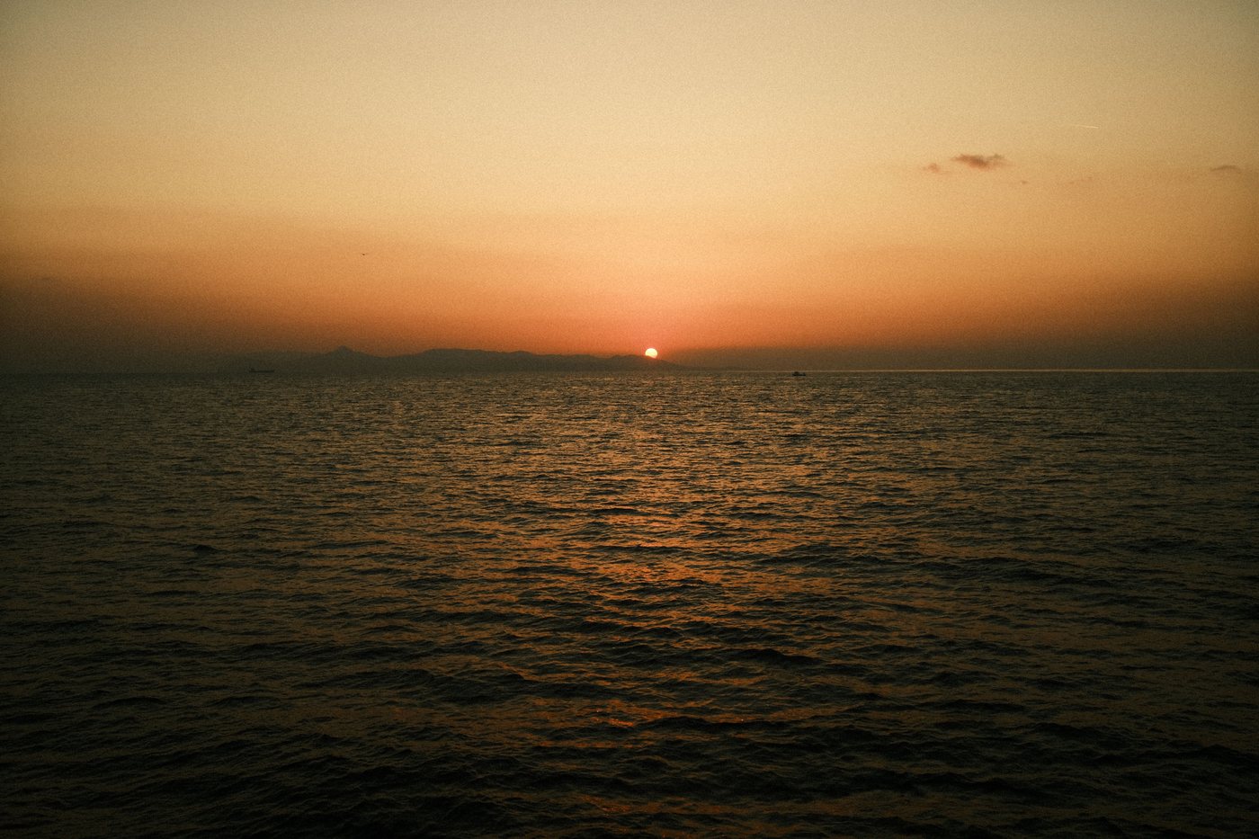 Tramonto sul mar Mediterraneo con una costa lontana all'orizzonte, simbolo del monitoraggio permanente dell'Osservatorio